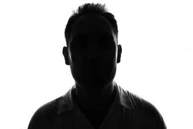 Uma silhueta mantendo o rosto oculto nas sombras