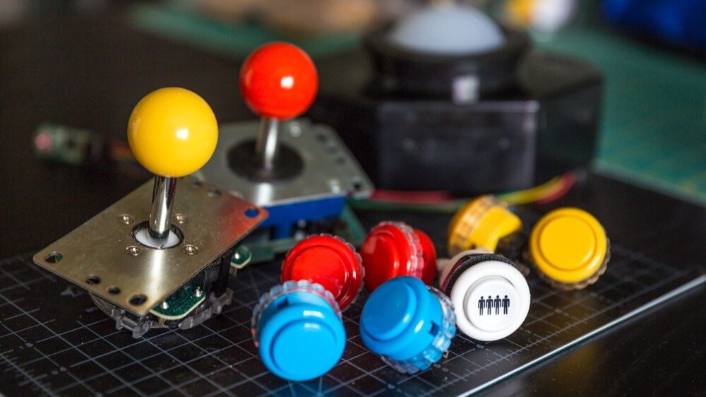 Foto de 2 controles direcionais e 7 botões coloridos.