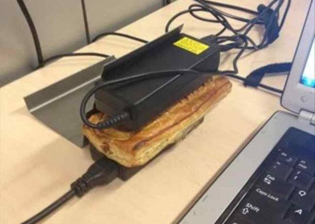 Foto de um sanduíche sendo aquecido pela fonte de um notebook.