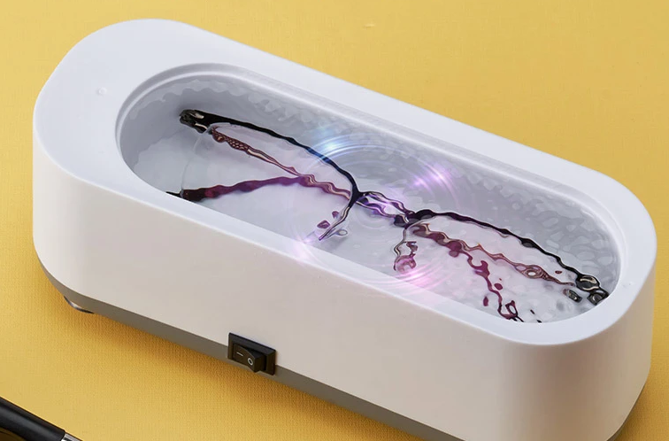 foto comercial do aparelho de banho ultrassônico sendo usado para limpar um óculos