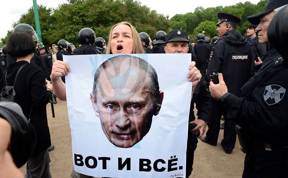 Foto de manifestante segurando cartaz com imagem de Putin