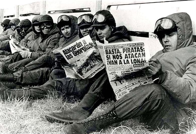 Foto em preto e branco: Soldados do exército argentino liam jornais em Port Stanley, durante a Guerra das Malvinas entre a Argentina e a Grã-Bretanha, em abril de 1982. REUTERS/Eduardo Farre<br>