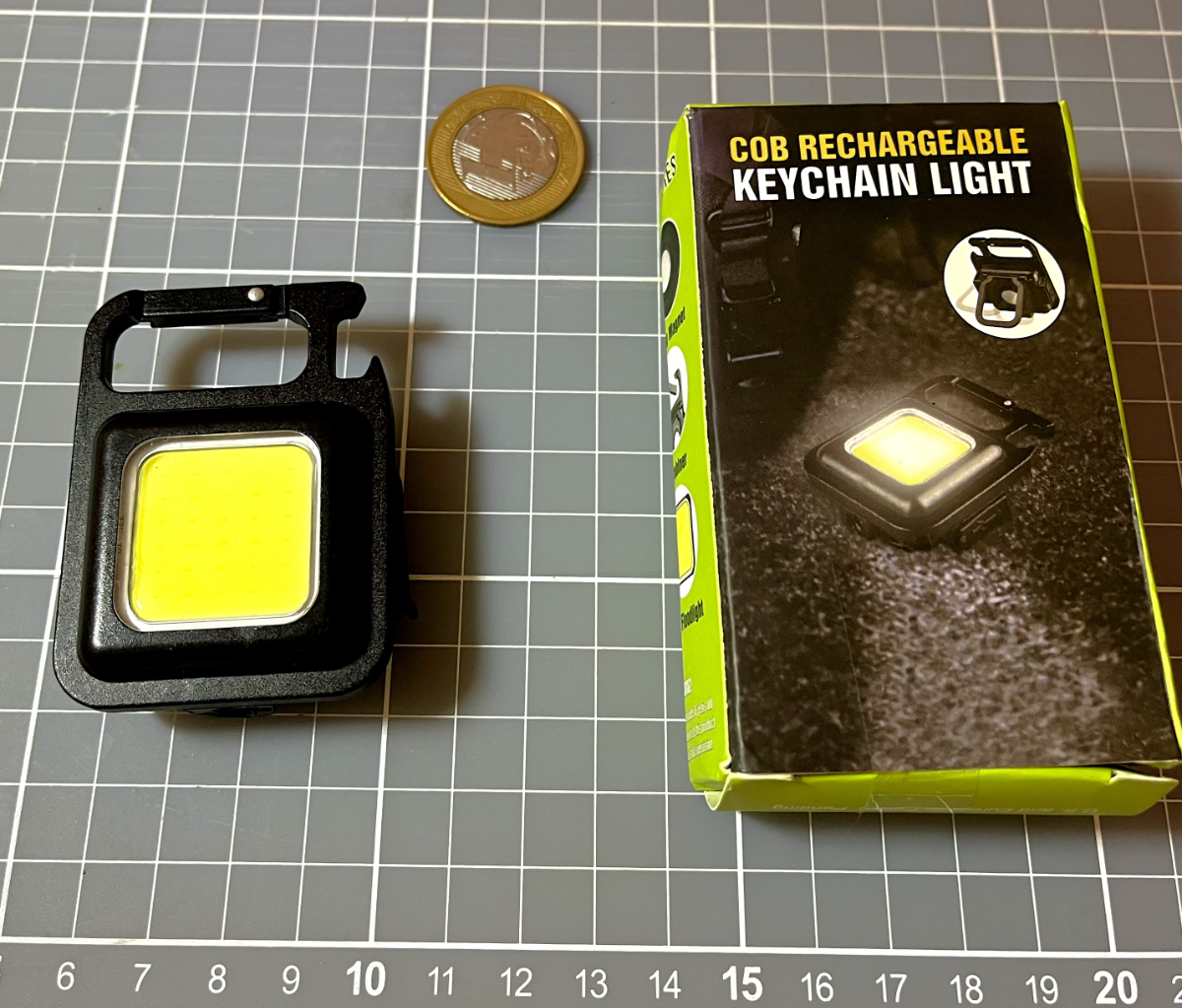 Foto da minha mini-lanterna descrita no post, ao lado da sua caixa, e de uma moeda de 1 real para a escala