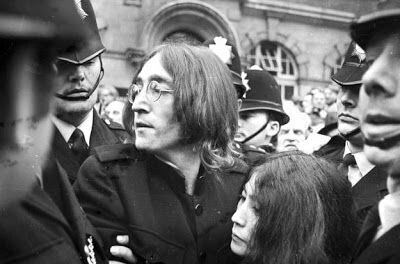Lennon sendo conduzido por policiais ingleses