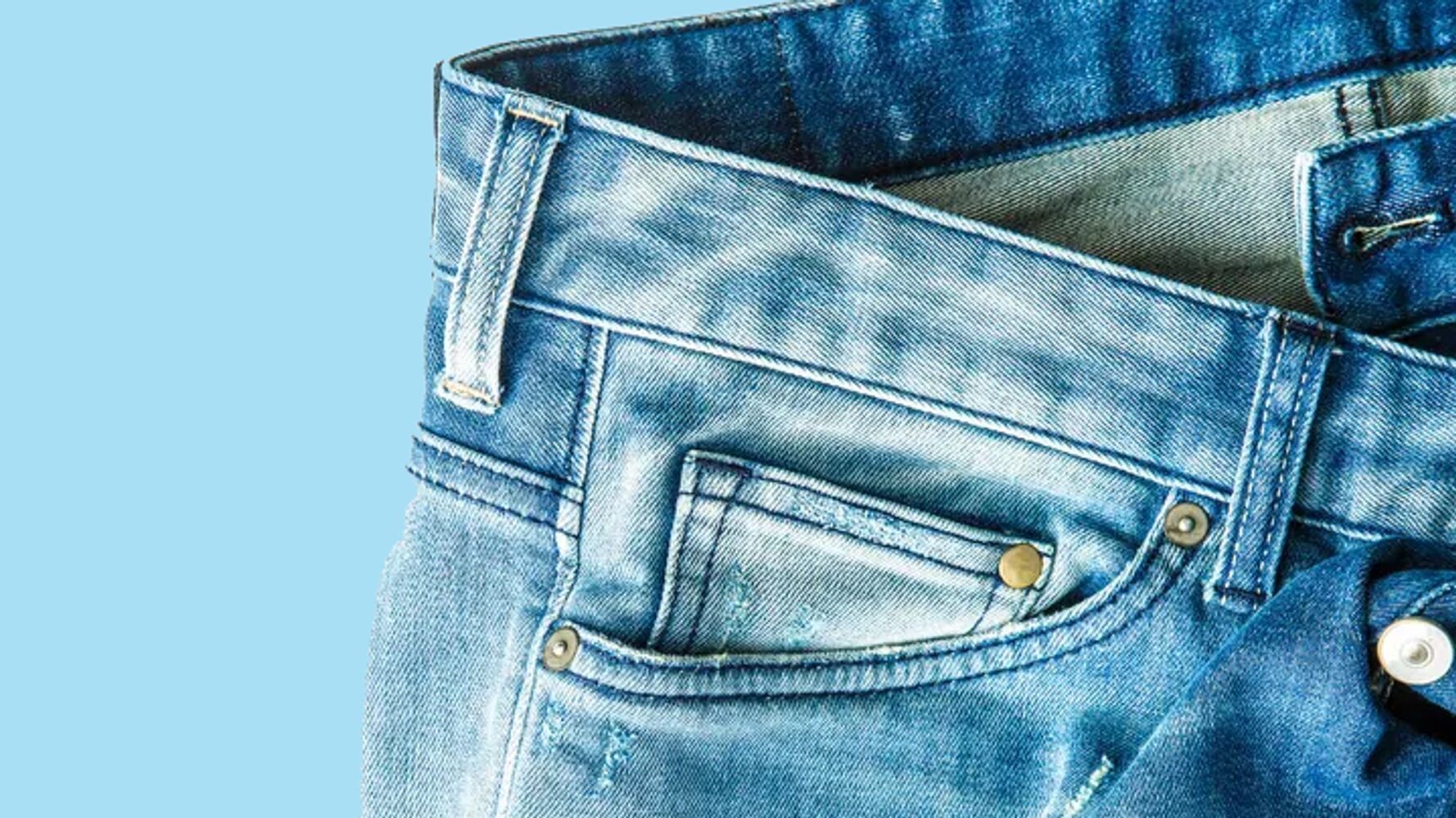 Detalhe de uma calça jeans exibindo os rebites metálicos no bolso frontal direito