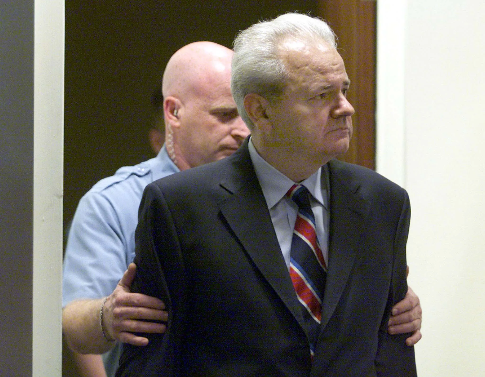 Slobodan Milosevic conduzido por guarda no Tribunal.