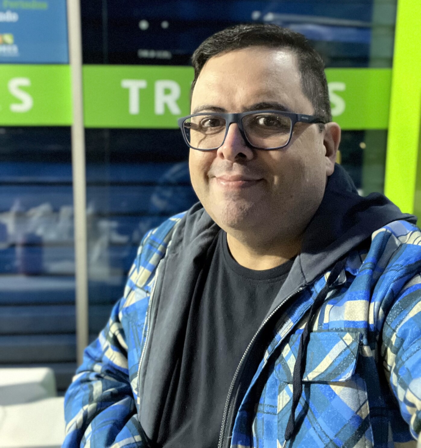 Selfie de casaco azul, camiseta azul e oculos de aro azul em frente a uma porta azul