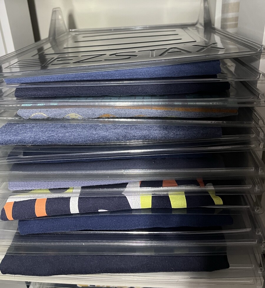 pilha de camisetas dobradas e com separador, todas azuis, senso uma delas com estampa colorida do Duran Duran