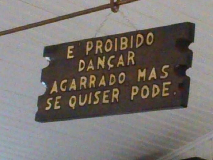 Placa pendurada no teto dizendo: é proibido dançar agarrado mas se quiser pode