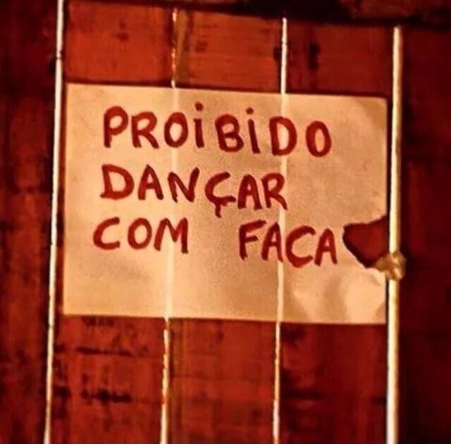 Placa na parede, escrito “Proibido dançar com faca“