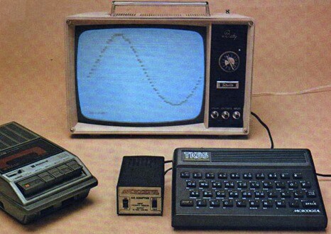 Um TK85 ao lado de um gravador de fita K7 e em frente a uma TV mostrando uma senóide