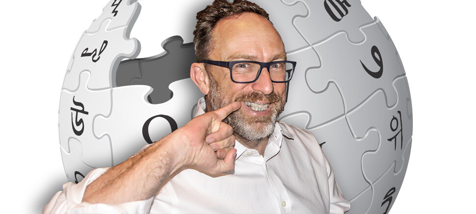 O sorridente Jimmy Wales faz pose de vilão de filme emn frente ao logo da Wikipedia
