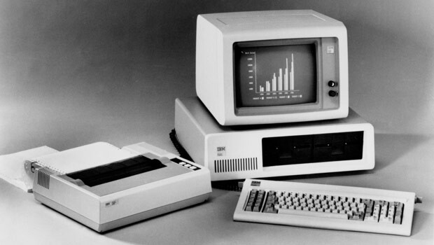 Foto em preto e branco de um IBM PC ao lado de uma impressora matricial