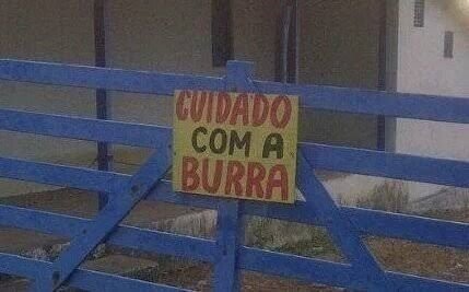 Porteira com placa escrito “CUIDADO COM A BURRA“