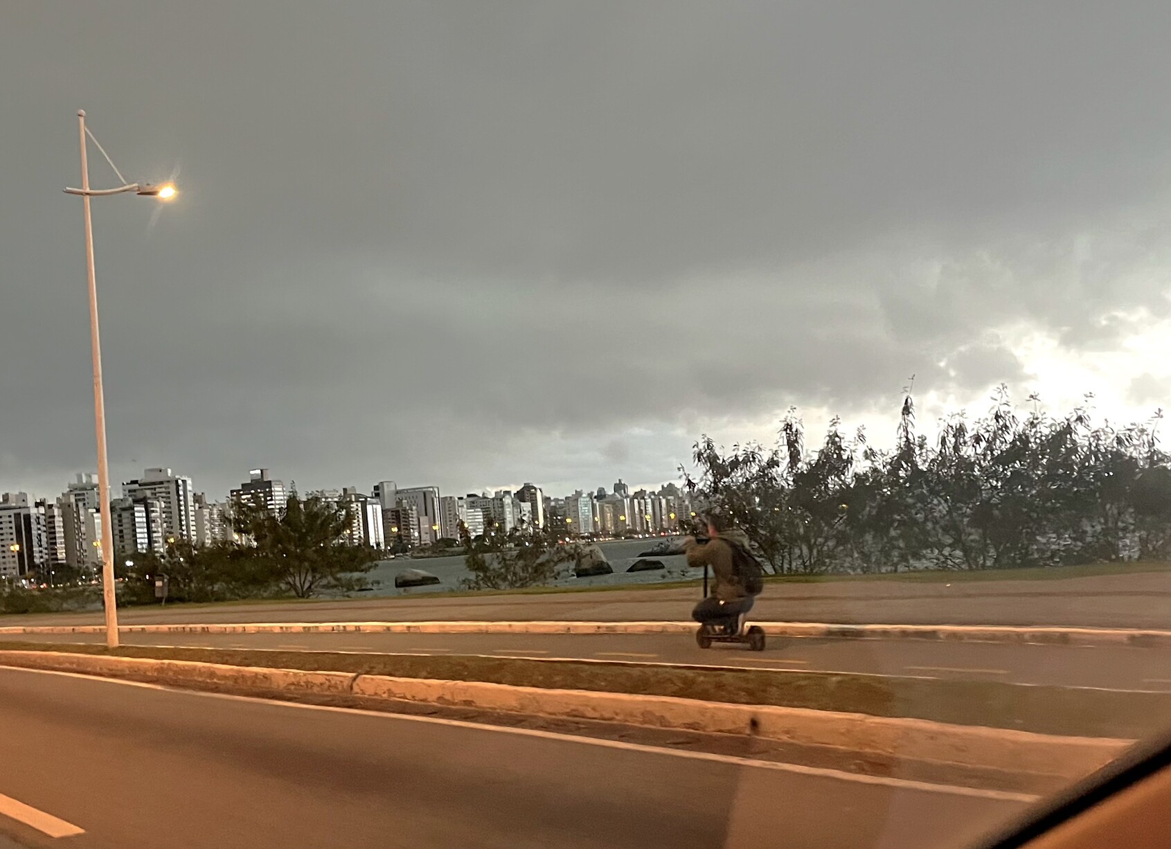 Homem abaixado em patinete elétrico na ciclovia, minutos antes da tempestade 