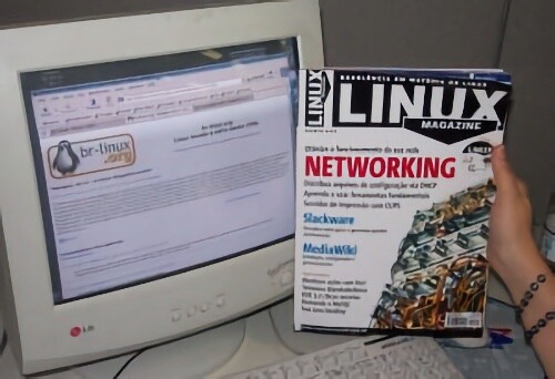 Mão feminina segura revista Linux Magazine, cujo destaque de capa é a palavra NETWORKING, ao lado de um monitor LG exibindo o site BR-Linux