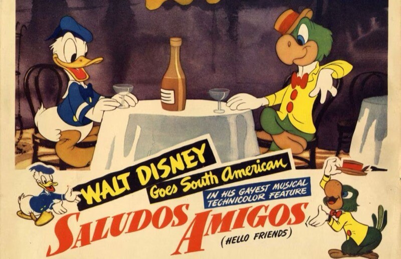 Uma imagem de Donald e Zé Carioca, em publicidade de 'Alô, Amigos' (1941), com a legenda: “WALT DISNEY Goes South American IN HIS GAYEST MUSICAL TECHNICOLOR FEATURE Saludos Amigos (HELLO FRIENDS)<br>