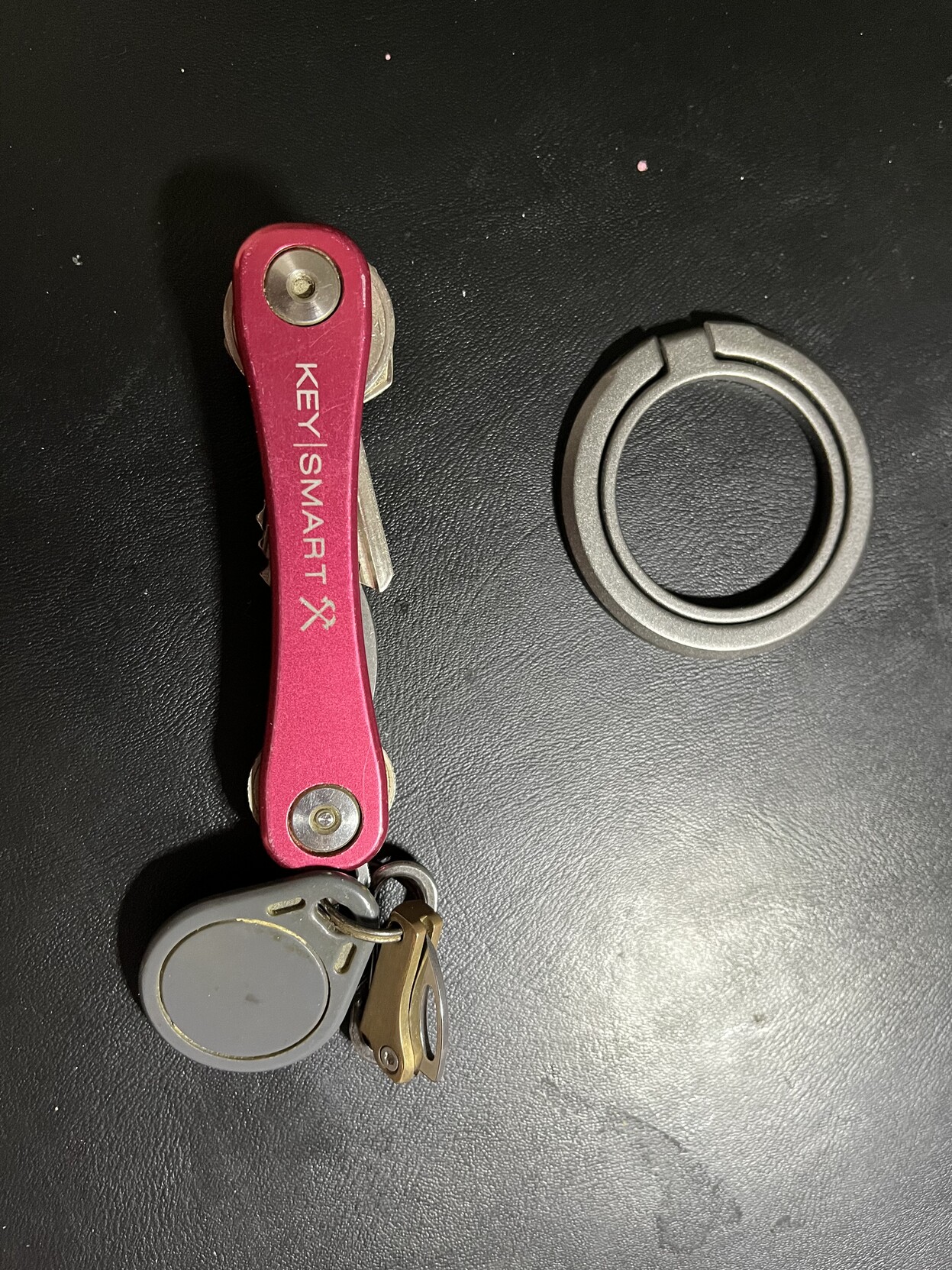 Chaveiro em tom rosa elétrico, ao lado de um acessório de celular que estava ali por perto