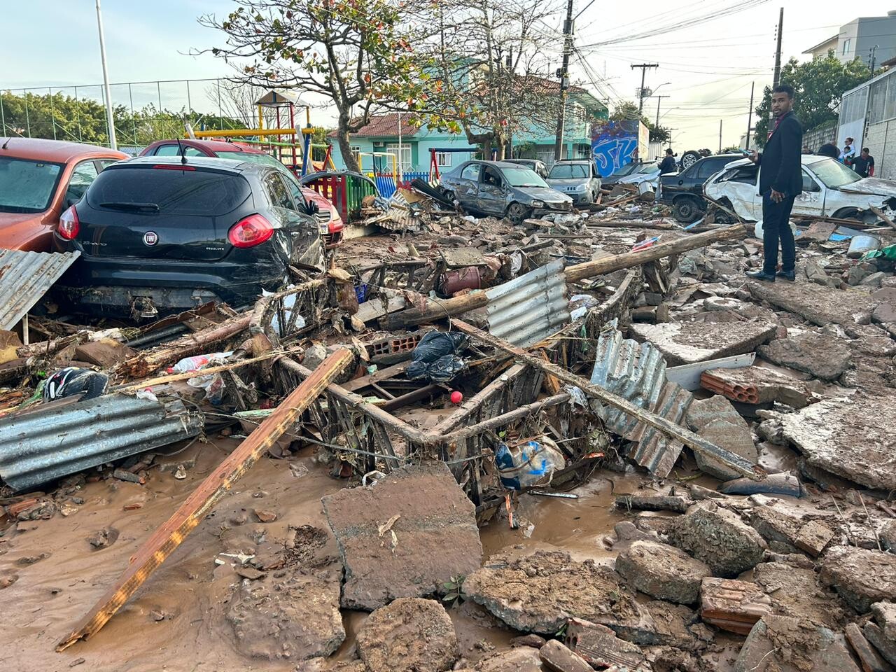 Foto jornalística mostra destroços, lama, fragmentos de alvenaria e de telhados, vários carros arrastados e amassados