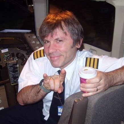Bruce Dickinson no cockpit, de uniforme de piloto e atitude rock'n'roll, sorri para a câmera