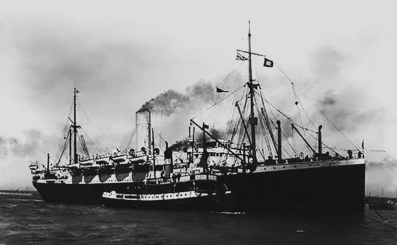Foto em preto e branco do navio Demerara, com fumaça de sua chaminé principal indo em direção à sua proa.