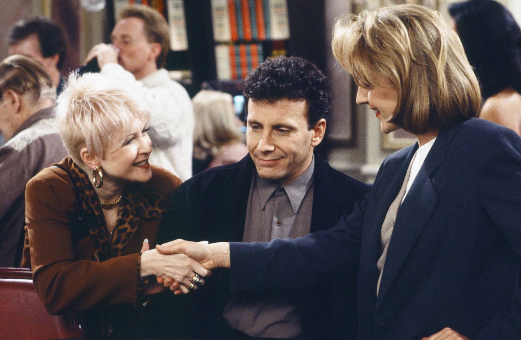 O personagem Paul faz careta enquanto a esposa Jamie cumprimenta a personagem de Cyndi Lauper.