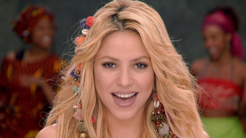 Shakira sorri, com enfeites coloridos no cabelo, em clipe de 72MB