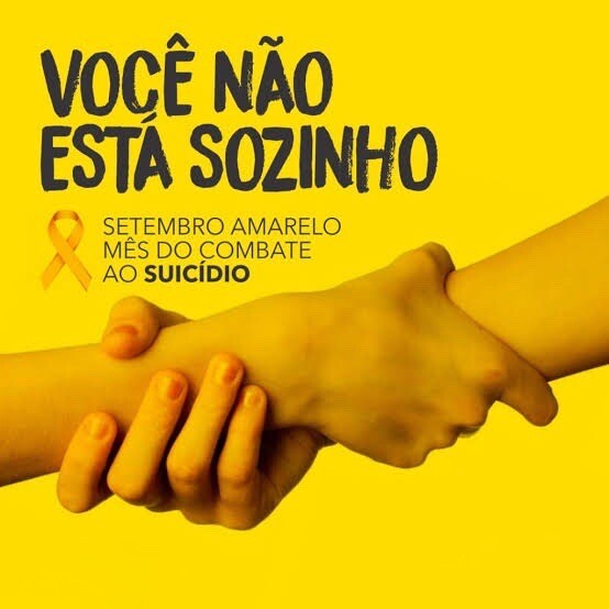 Duas mãos em um aperto firme, sobre fundo amarelo, com a frase: Você não está sozinho - setembro amarelo, mês de combate ao suicídio