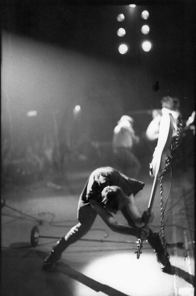 Paul Simonon, no palco, segura seu baixo pelo braço, prestes a batê-lo contra o chão