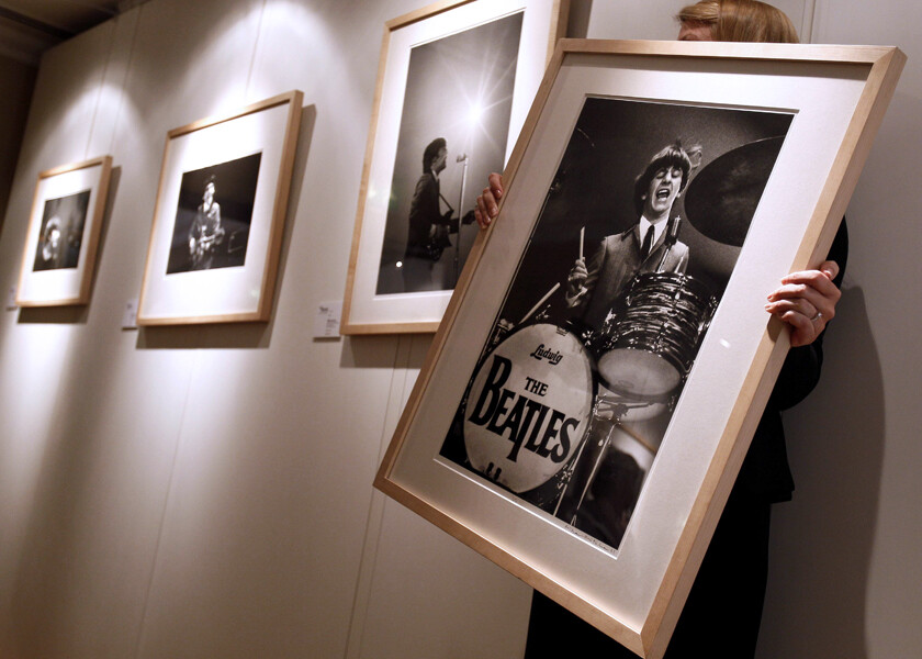 Foto de uma pessoa organizando quadros de uma exposição comemorativa dos 50 anos da chegada dos Beatles aos Estados Unidos, em Nova York.<br>