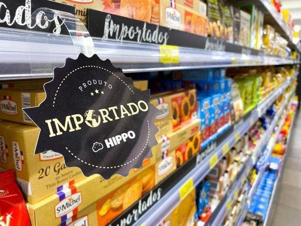 Etiqueta destaca produtos importados em gôndola de biscoitos, em supermercado perto da minha casa