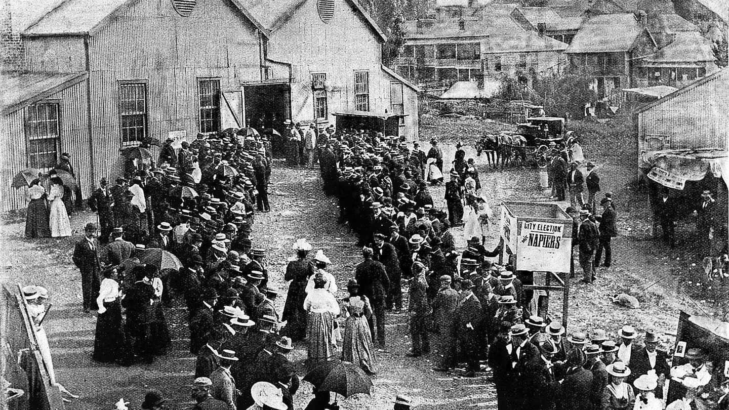 Foto panorâmica: Fortemente superadas em número pelos homens, as mulheres compareceram a uma cabine de votação de Auckland em novembro de 1893 para votar em sua primeira eleição depois de garantir o direito ao voto.
