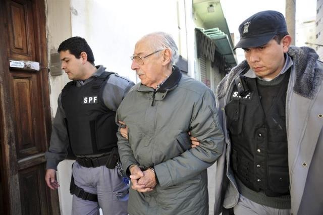 Videla é levado pela polícia em San Martin na época em que foi condenado a 50 anos de prisão pelo rapto de bebês<br>