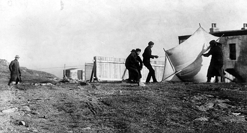 Foto em preto e branco de Guglielmo Marconi e associados preparando a antena receptora fixada em uma pipa em St. John's, Terra Nova, em dezembro de 1901 em preparação para sua histórica primeira transmissão de rádio transatlântica.<br>