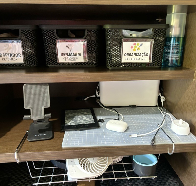 Cabos de carregadores diversos ao redor de uma caixa contendo os adaptadores AC de uma série de aparelhos com bateria usados na minha casa