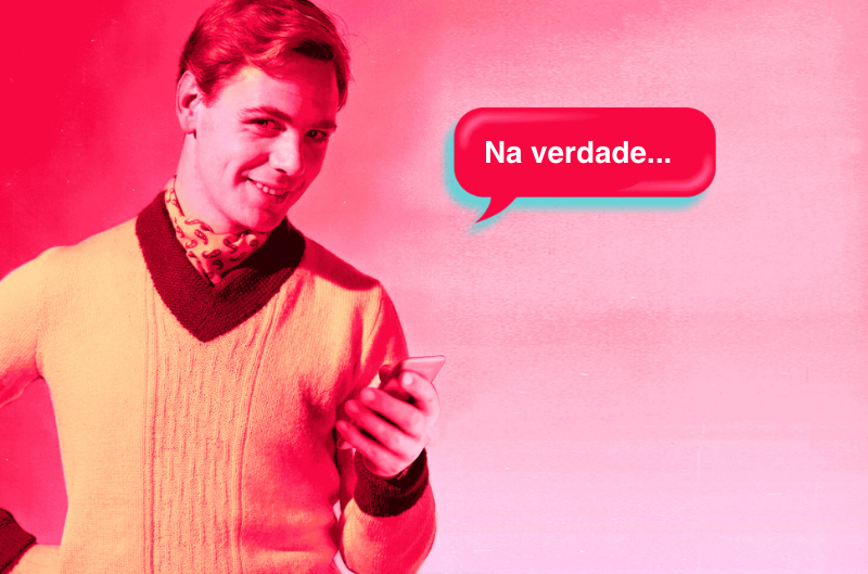 Um cara de meia idade, vestido no estilo chique despojado dos anos 50, de pulôver e com lenço de seda no pescoço, dizendo: “Na verdade...“