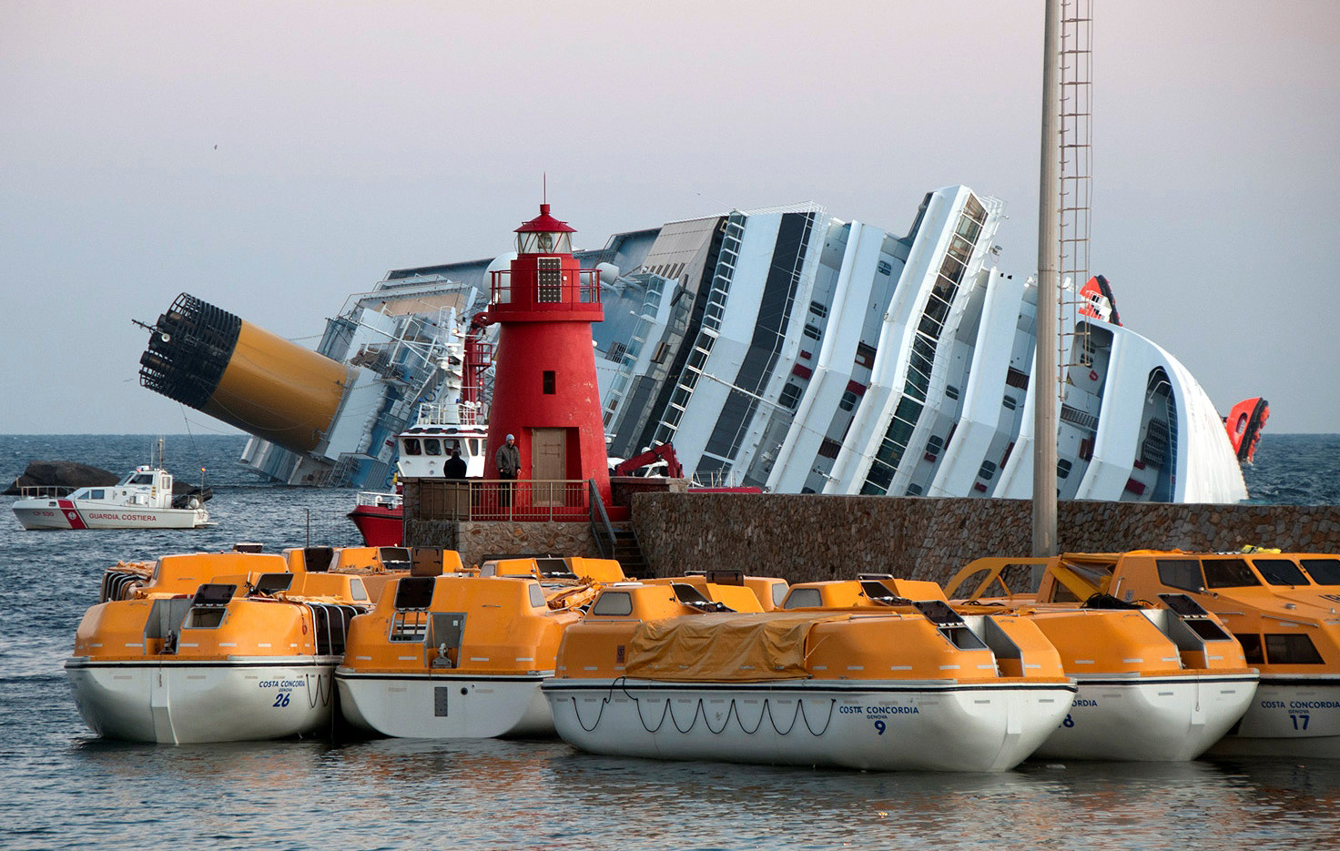 Os botes salva-vidas do Costa Concordia, com o navio ao fundo, adernado a quase 90 graus.