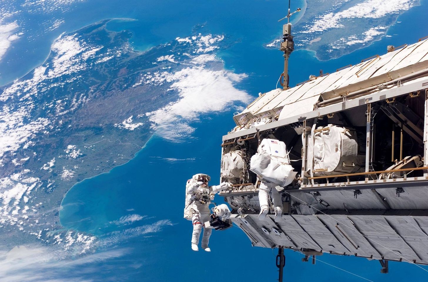 Dois tripulantes da ISS em atividade externa, com a Terra ao fundo