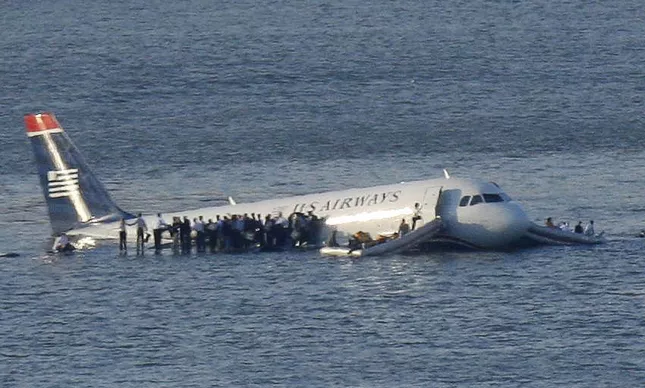 Passageiros e tripulantes aguardam resgate na asa e nas saídas de emergência do Airbus que flutua na superfície do rio.