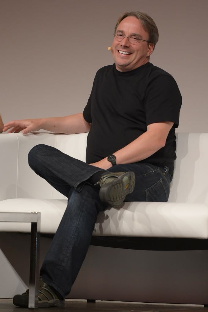 Linus Torvalds, com um microfone, sorri para o público.