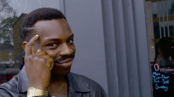 O personagem do meme Genius Black Guy, sorrindo e tocando com o indicador a sua própria têmpora.