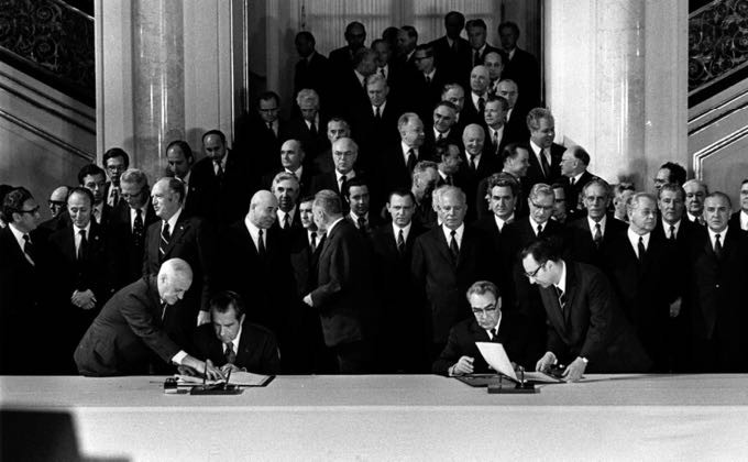 Foto em preto e branco da assinatura do tratado, com Brezhnev, Nixon e dezenas de engravatados