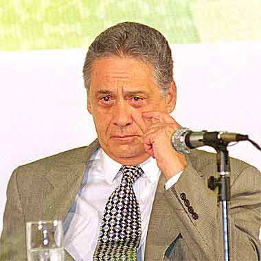 FHC leva a mão esquerda ao rosto, abaixo dos olhos.