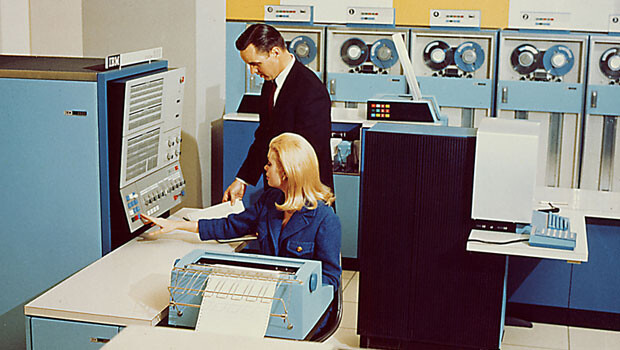 Foto promocional mostrando um homem e uma mulher operando um mainframe da IBM.