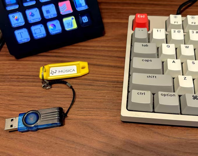 Foto de um pen drive azul preso a um identificador de chaves no qual consta uma etiqueta com a palavra “Música“