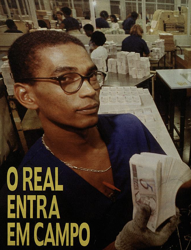 Funcionário do parque gráfico da Casa da Moeda posa com maço de cédulas de 5 reais, em foto jornalística com a legenda “O Real Entra em Campo“