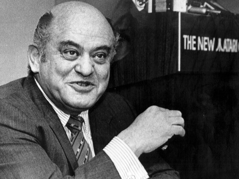 Jack Tramiel ao lado de um púlpito em que está escrito The New Atari