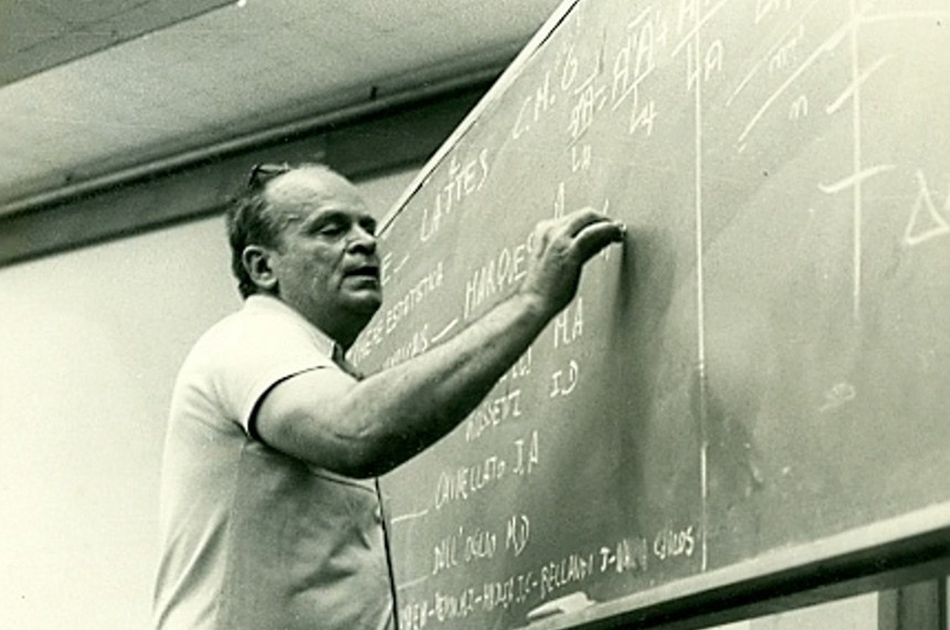 César Lattes escreve com giz em um quadro.