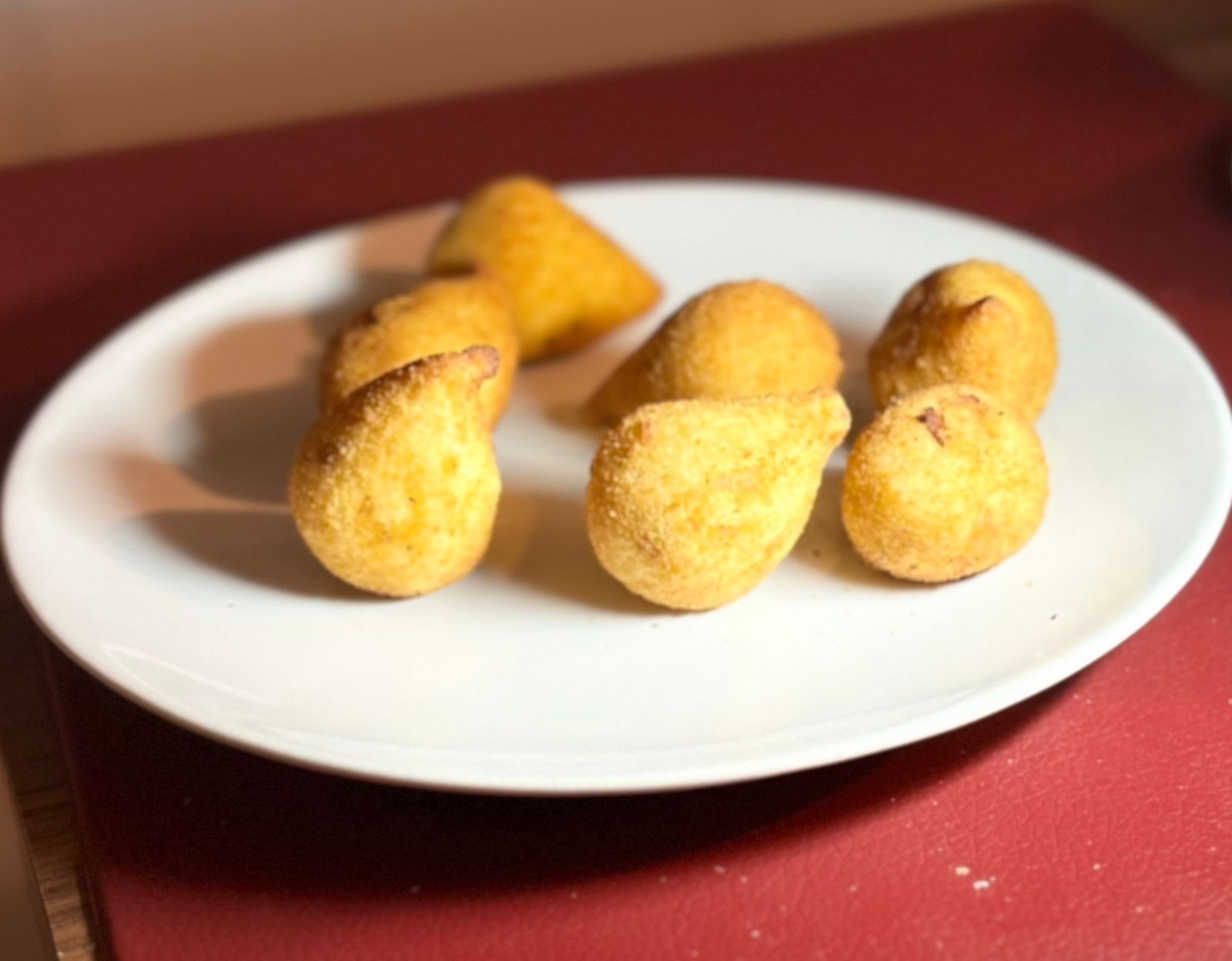 Um prato pequeno contendo 7 mini-coxinhas de festa