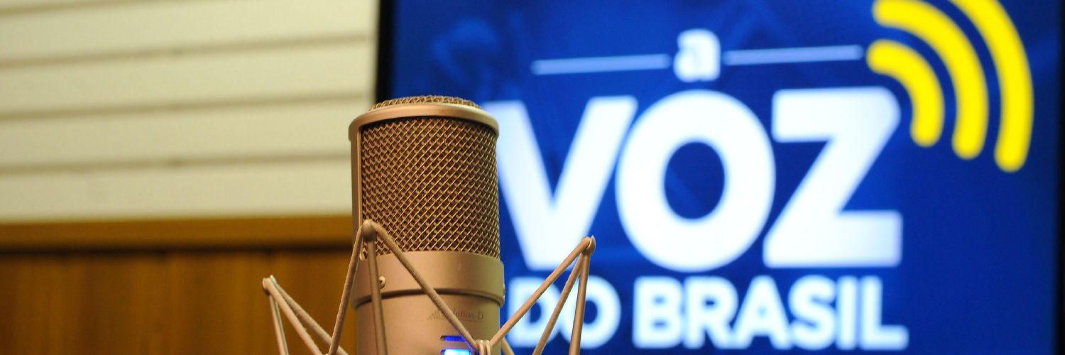 Microfone radiofônico e banner da Voz do Brasil ao fundo